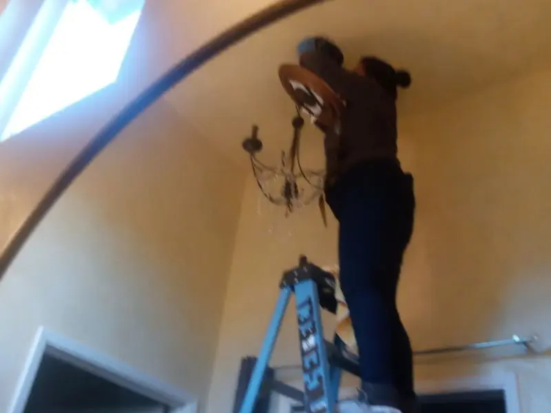 Electrician installing a chandelier in a Wharton residence